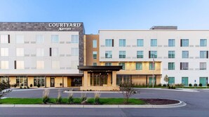 A Courtyard Marriott hotel with a modern design, featuring a central entrance, multiple floors, and a parking area.