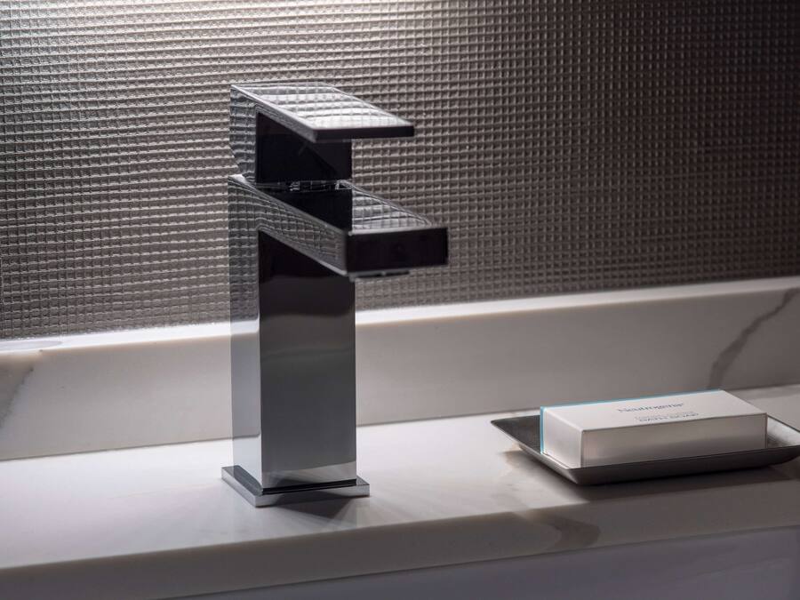 A modern bathroom with a sleek, metallic faucet and a box of toiletries on the counter.