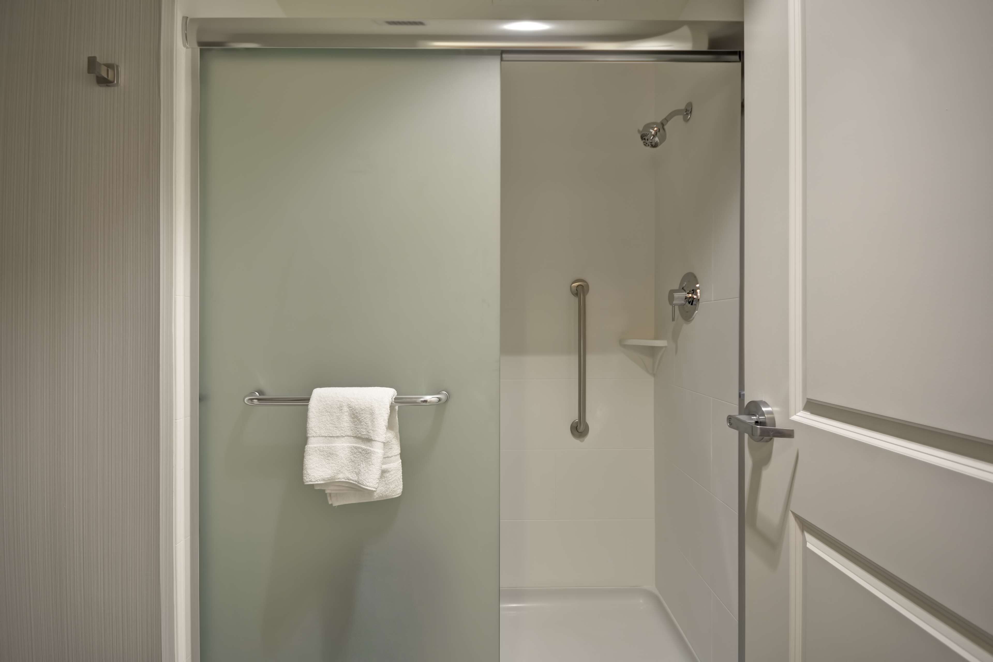 Une salle de bain moderne avec une douche à parois de verre, un porte-serviettes et une baignoire.