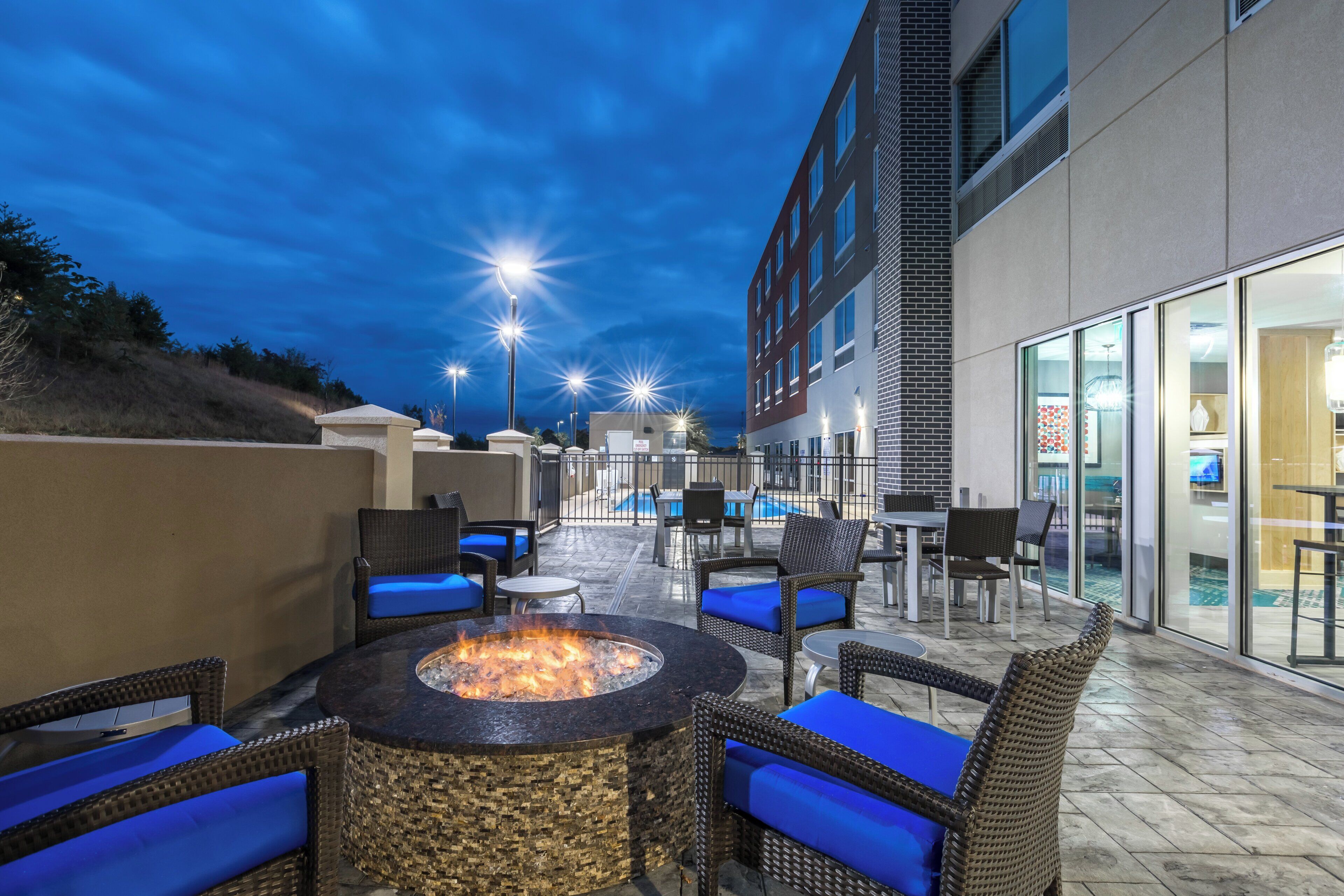 Un área de patio al aire libre con una chimenea, asientos y una piscina.