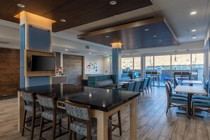 A modern interior with a bar area, seating, and a television. - Holiday Inn Express & Suites Gainesville - Lake Lanier Area by IHG (Gainesville)