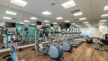 Un gimnasio con numerosas cintas de correr, elípticas y pelotas de ejercicios.