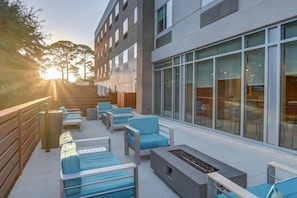 An outdoor seating area with modern furniture, a fire pit, and a building with large windows. - Holiday Inn Express Fort Walton Beach Central by IHG (Fort Walton Beach)