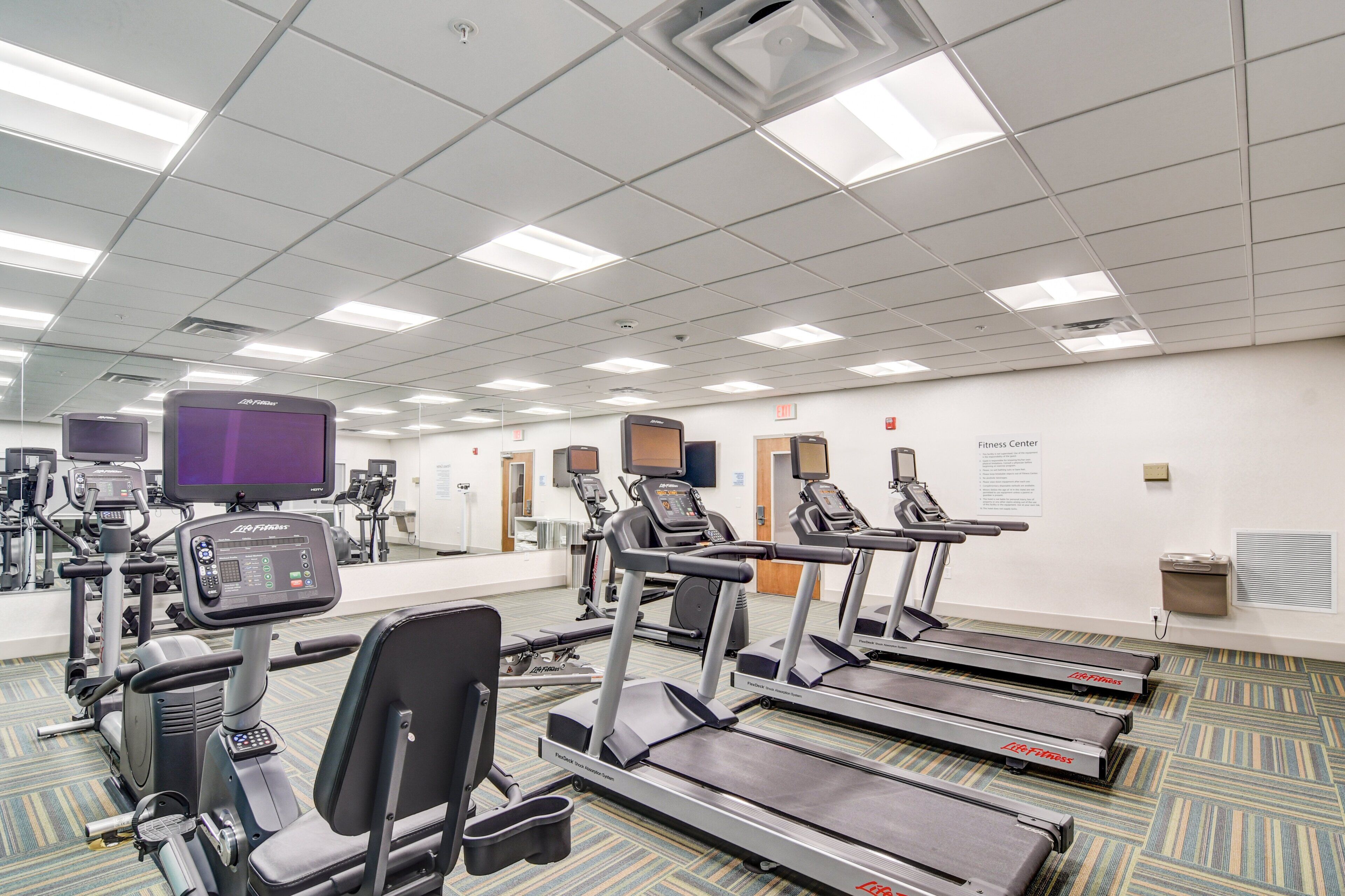 Un centre de remise en forme équipé de tapis de course, de vélos elliptiques et d'appareils de musculation.
