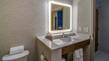 Un baño con un lavamanos blanco, un espejo y un inodoro.