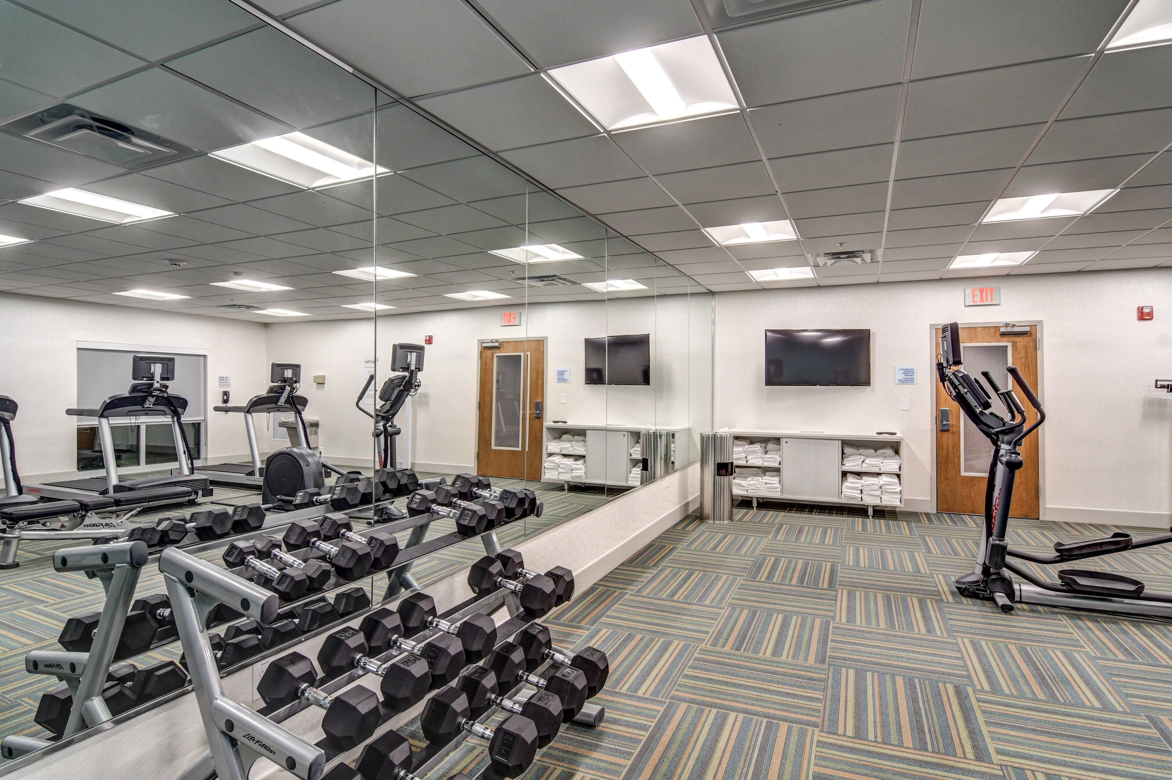 Een hotel fitnessruimte met loopbanden, gewichten en trainingsapparatuur.