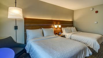 Una habitación de hotel con dos camas, un escritorio y una lámpara.