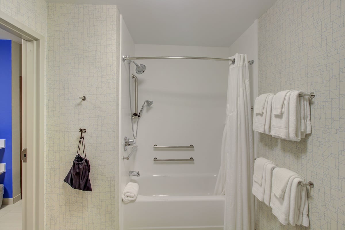 A bathroom with a bathtub, shower, and towel rack.