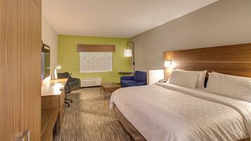 Een hotelkamer met een bed, een bureau, een stoel, een lamp en een raam met zonwering.