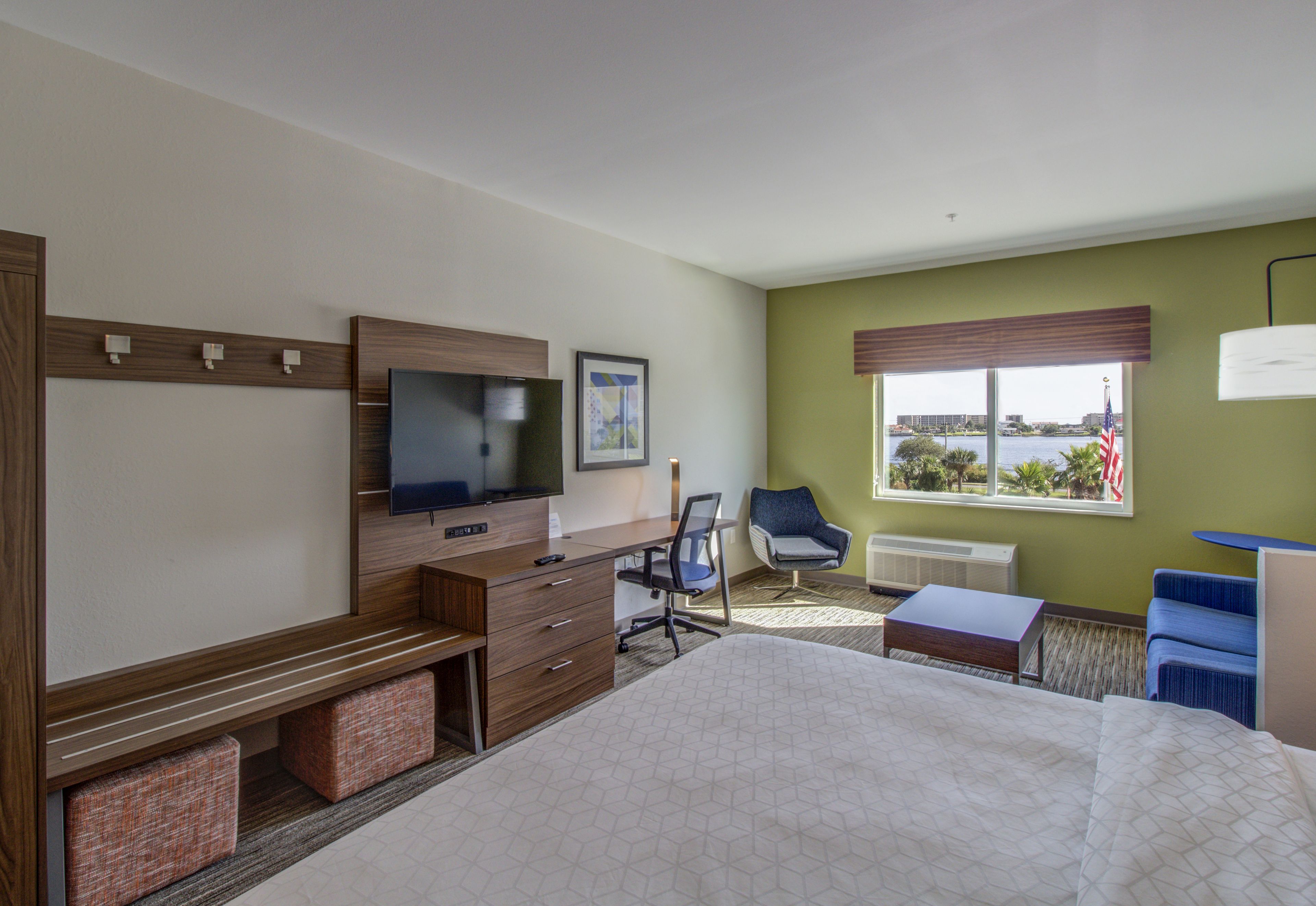 A hotel room with a bed, desk, chair, television, and a window with a view.
