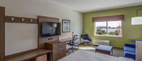A hotel room with a bed, desk, chair, television, and a window with a view.