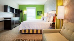 A hotel room with a bed, a desk, a chair, a TV, and a lamp.