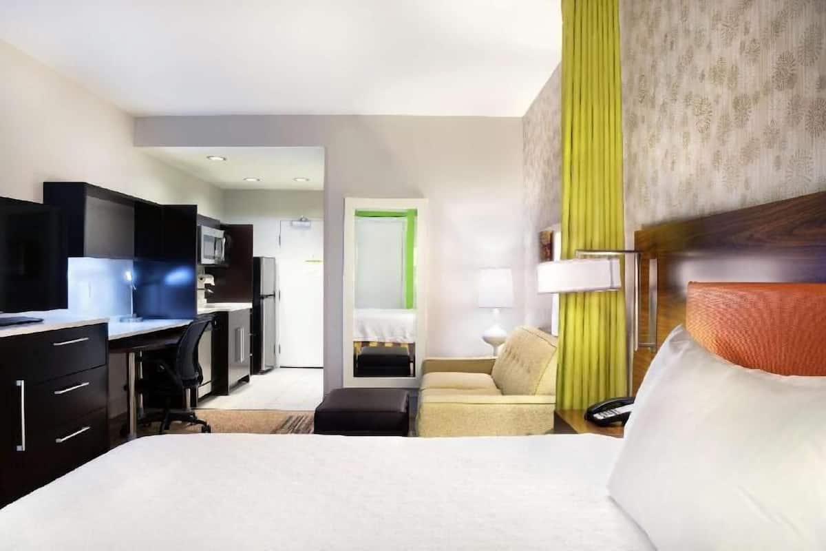 Une chambre d’hôtel comprenant un lit, un bureau avec un ordinateur, une chaise, un canapé, une lampe et un téléviseur.