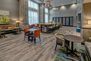 Relax in our inviting lobby, featuring a communal dining area, large windows, and a contemporary art piece.