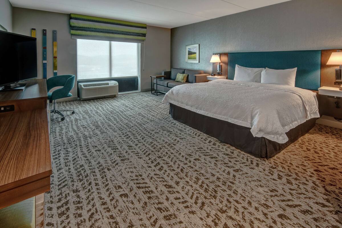Hotelkamer met een groot bed, een bureau, een stoel, een televisie en een raam met uitzicht.