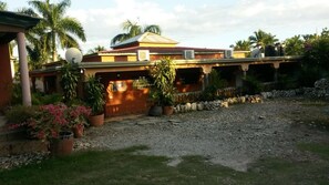A house with a red roof, satellite dish, and potted plants. - Le Jardin Hotel Restaurant (Jacmel)