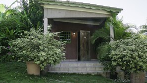 A house with a front porch, a door, and steps leading up to it. - Le Jardin Hotel Restaurant (Jacmel)