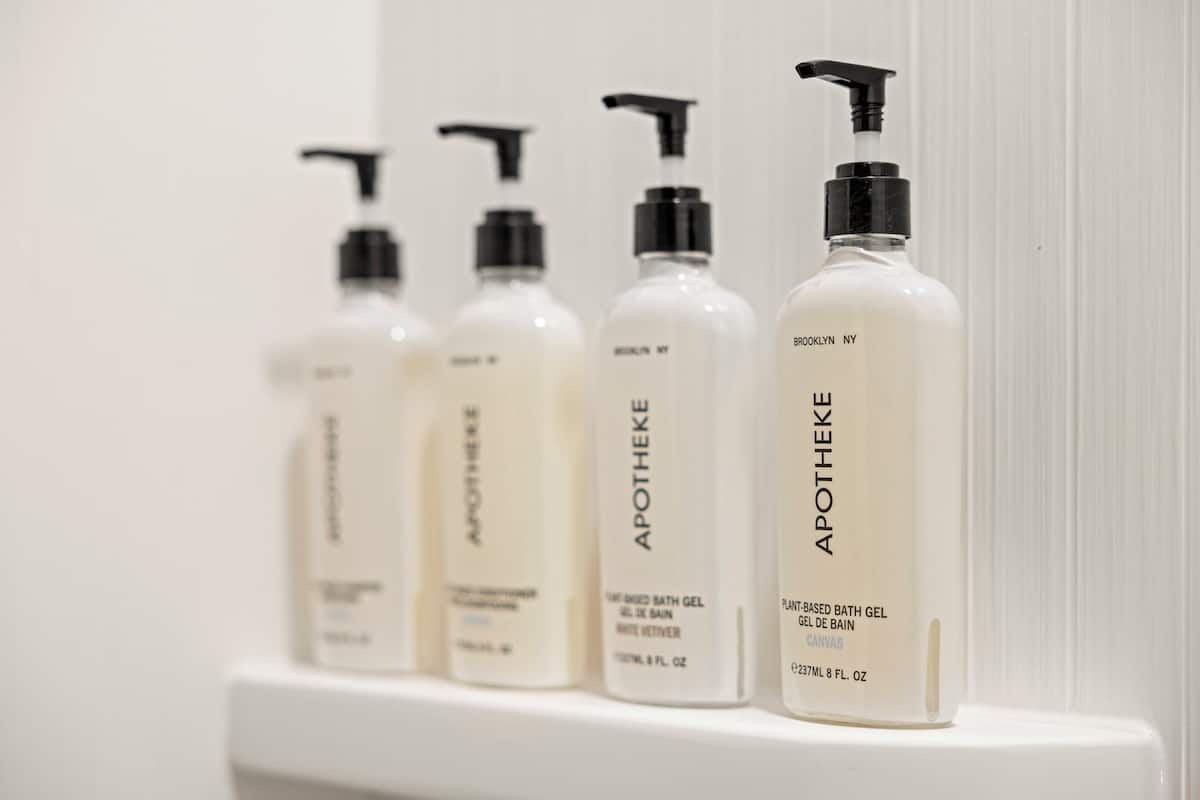 Four bottles of bath gel on a white shelf.