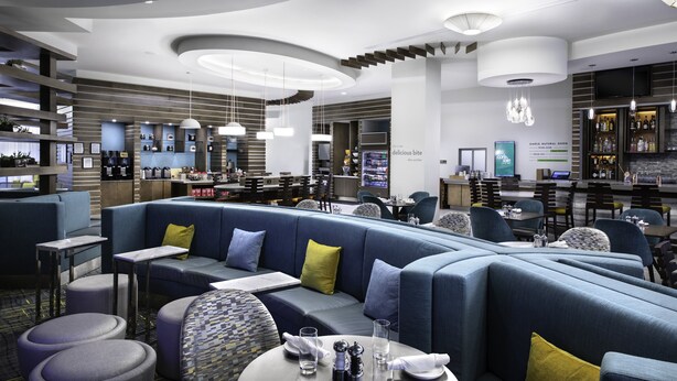 A modern restaurant with a curved seating area, bar, and a variety of dining options. - EVEN Hotel Miami - Airport by IHG (Miami)