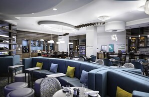 Un restaurant moderne doté d’un espace salon aux lignes courbes, d’un bar et offrant une variété de possibilités pour les repas.