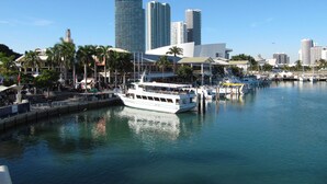 A marina with a white boat docked, surrounded by tall buildings and palm trees. - EVEN Hotel Miami - Airport by IHG (Miami)