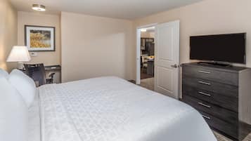 Ein Hotelzimmer mit einem Bett, einem Schreibtisch mit Lampe, einem Fernseher und einem Kleiderschrank.