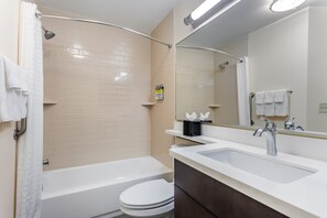 Une salle de bain moderne équipée d’une baignoire, de toilettes et d’un meuble-lavabo avec un évier.