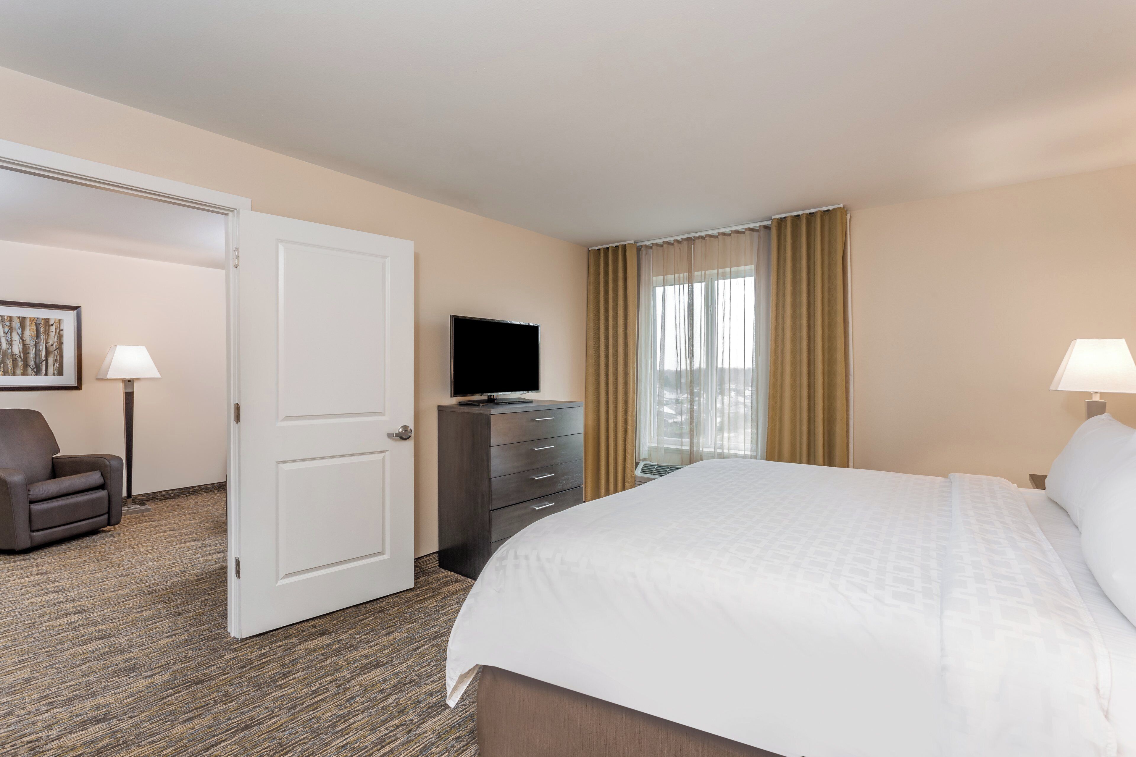 A hotel room with a bed, a dresser, a television, and a chair.