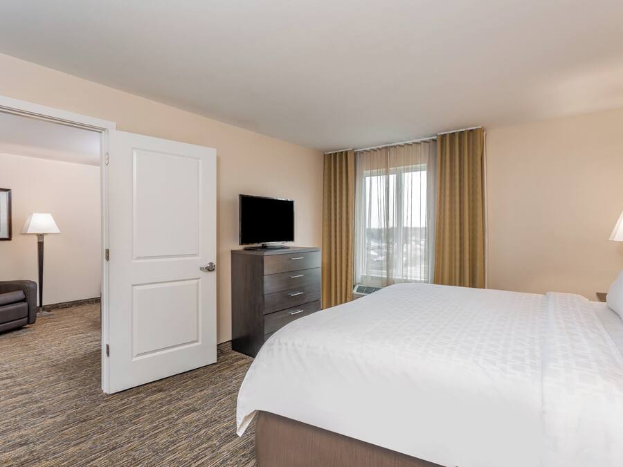A hotel room with a bed, a dresser, a television, and a chair.