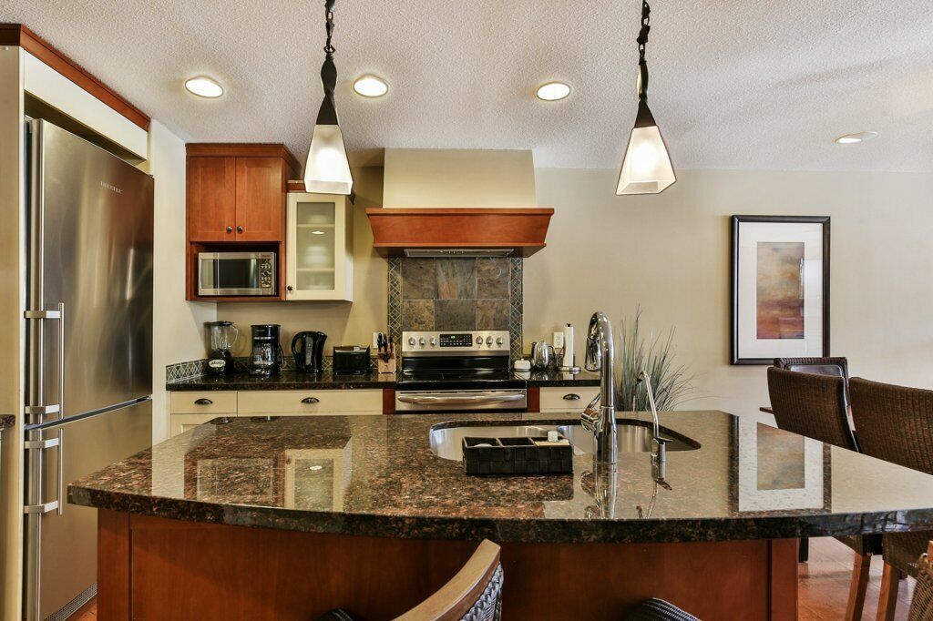 A modern kitchen with granite countertops, stainless steel appliances, and wooden cabinetry.