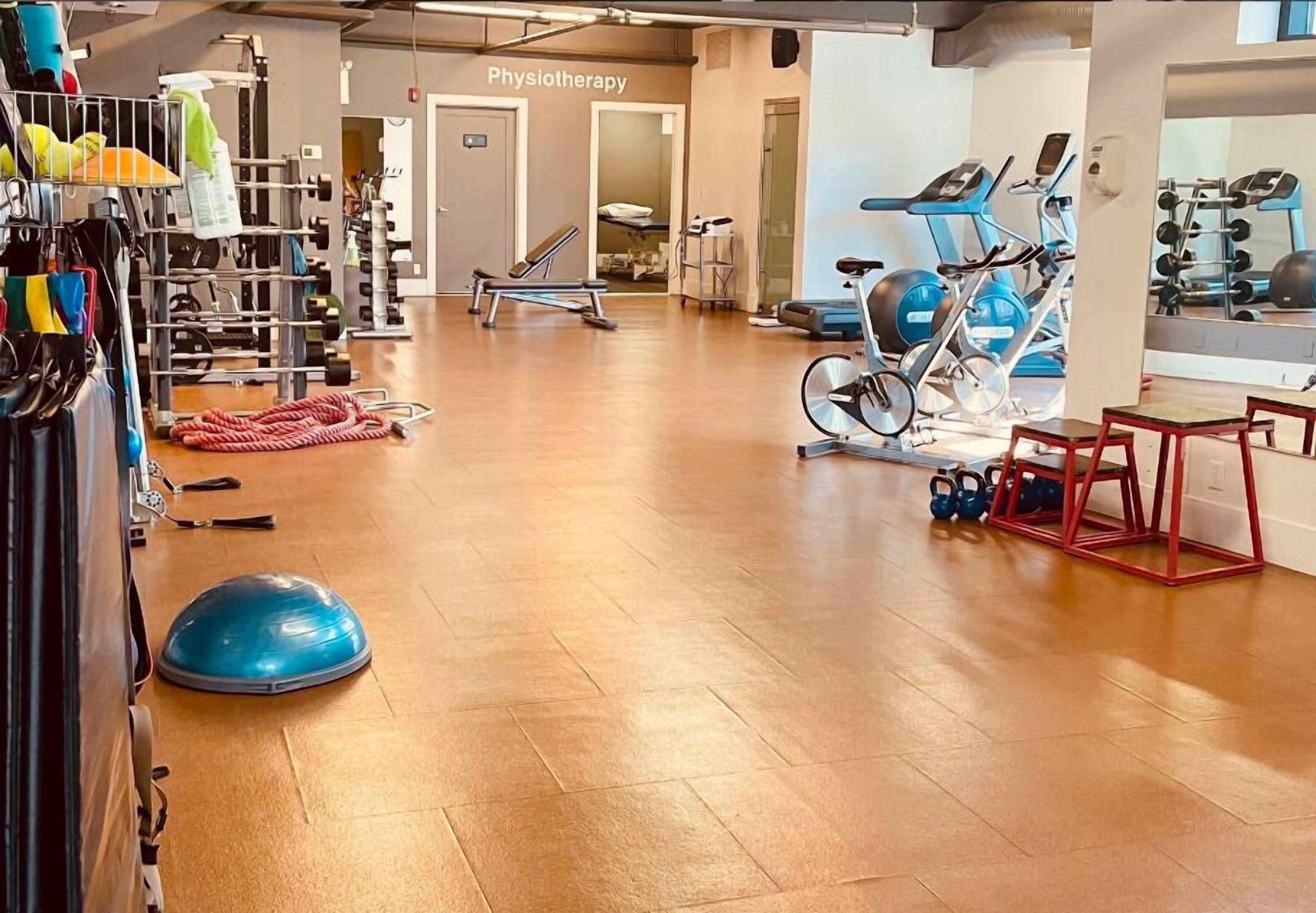 Une salle de sport équipée de matériel d’exercice, une salle de physiothérapie et un miroir qui reflète le matériel.