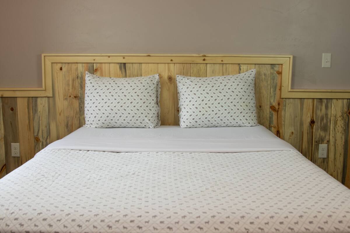 A bed with a wooden headboard and two pillows with a pattern.