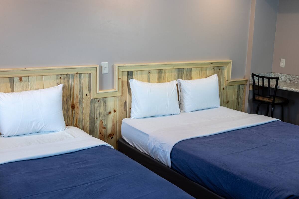 A room with two beds, each with a wooden headboard and white bedding.