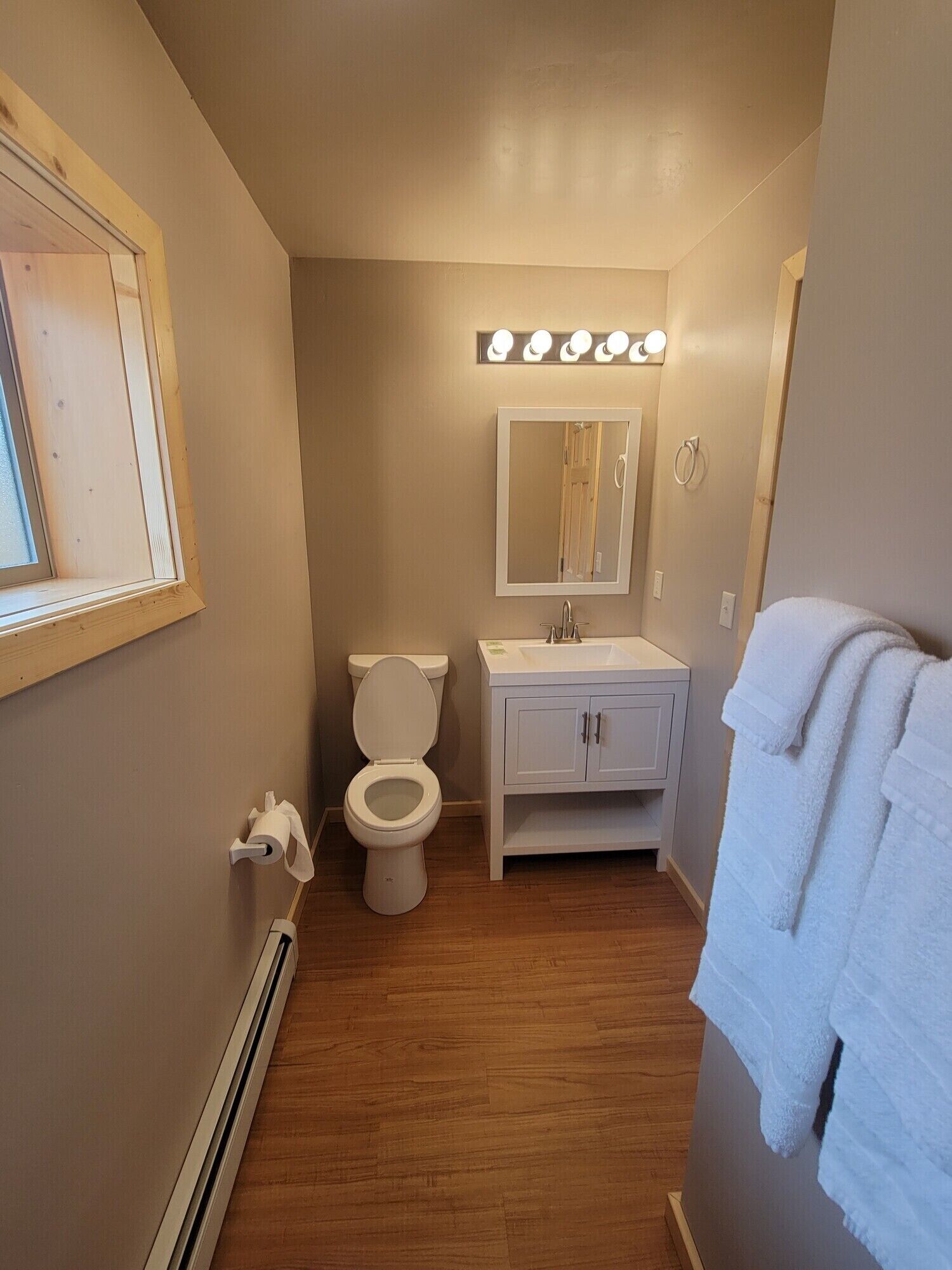 A small bathroom with a toilet, sink, mirror, and towel rack.