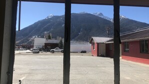 Vista a través de una ventana que muestra un estacionamiento con una montaña al fondo.