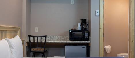 Habitació d'hotel senzilla amb un llit, una cuineta petita que inclou un microones, una cafetera i un mini-frigorífic.