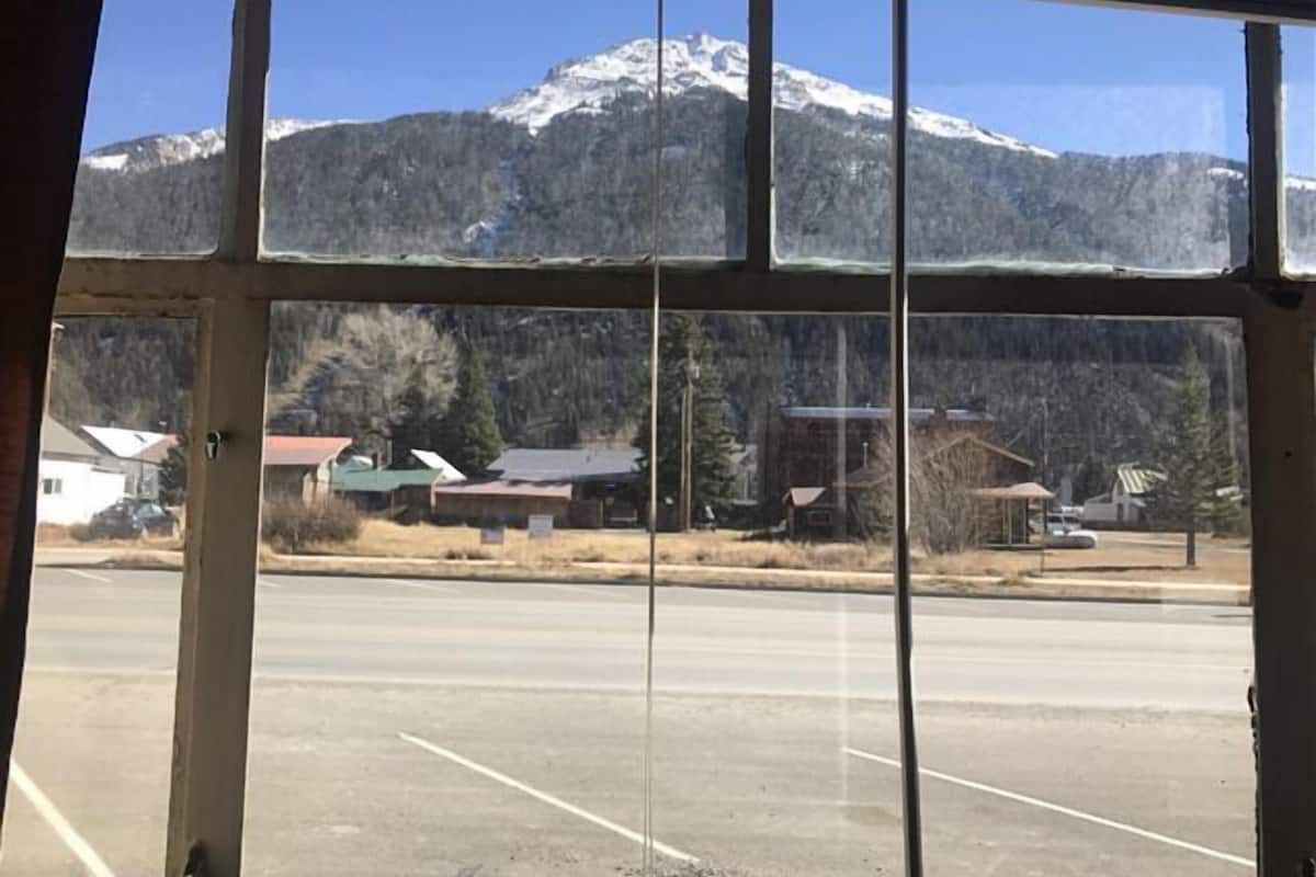 A view through a window of a parking lot with a mountain in the background.