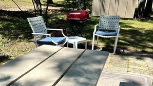 Een terras met een betonnen tafel en twee witte stoelen.