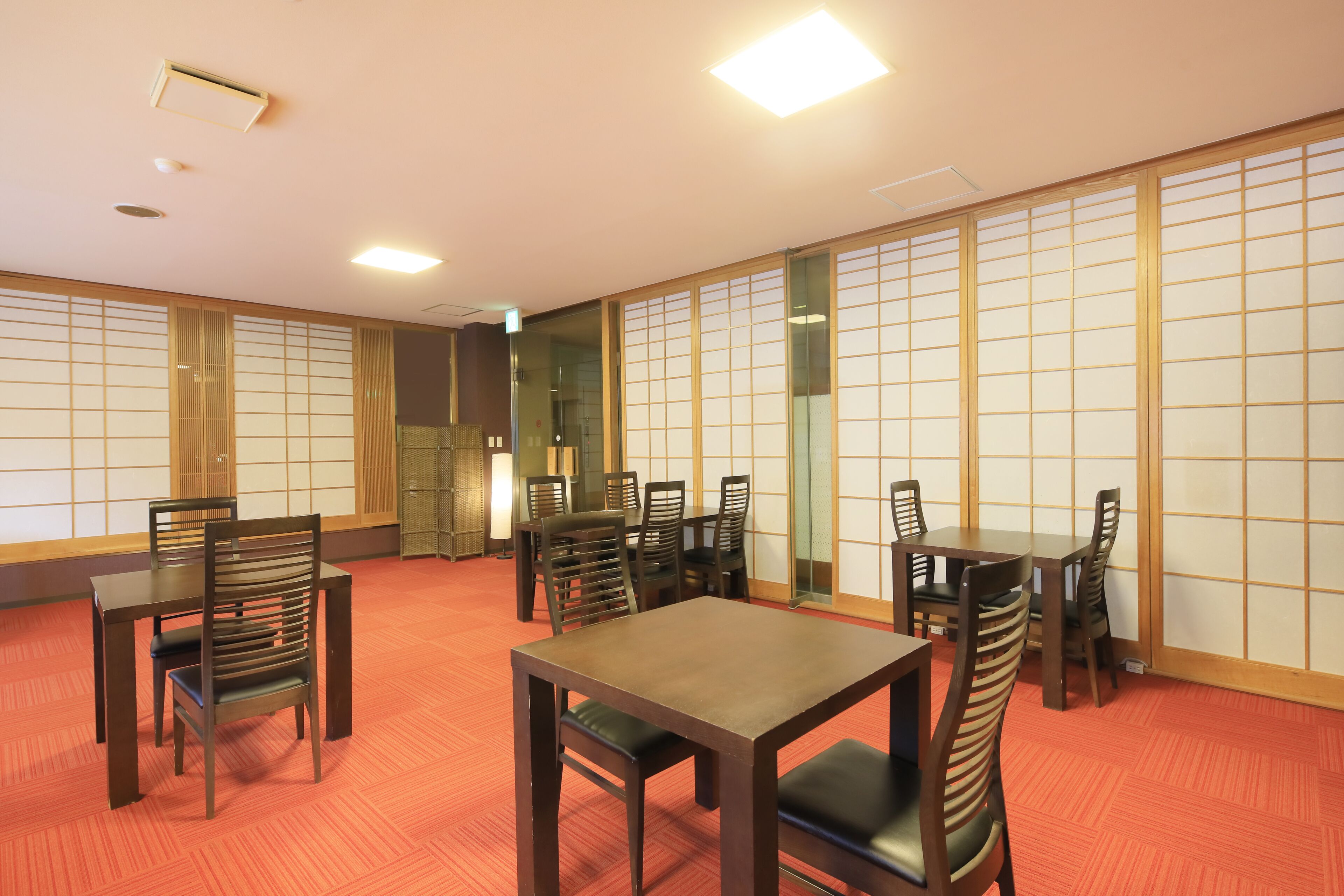 Una habitación japonesa tradicional con suelo de tatami, puertas correderas de madera y una mesa baja con sillas.