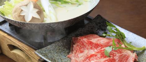 A bowl of soup with vegetables and a piece of meat on a plate.