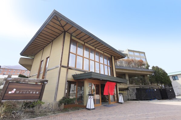 Un bâtiment japonais traditionnel, doté d’une façade en bois, de grandes fenêtres et d’une entrée abritée.