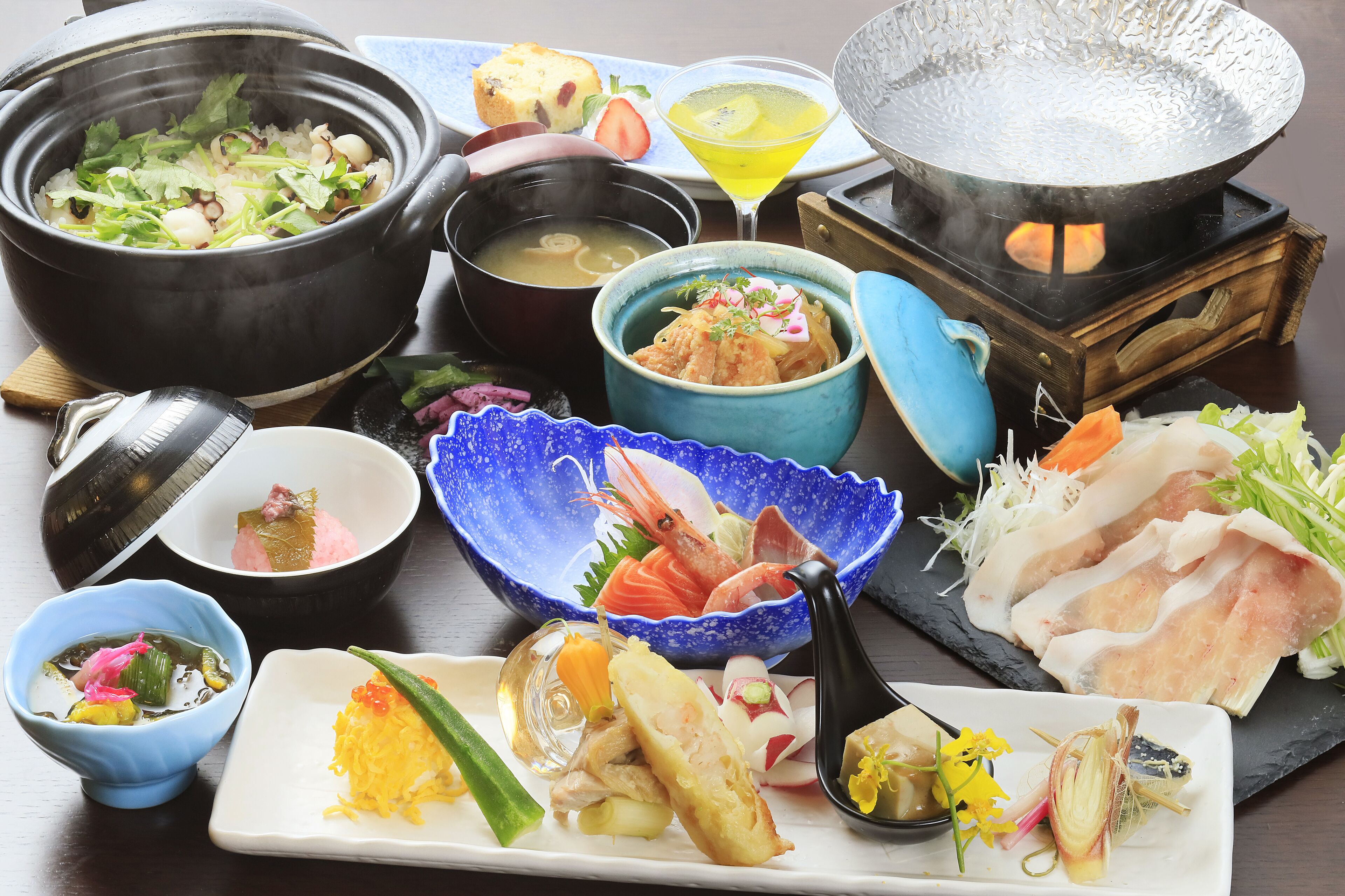 A variety of Japanese dishes including a hot pot, sashimi, and a martini glass.