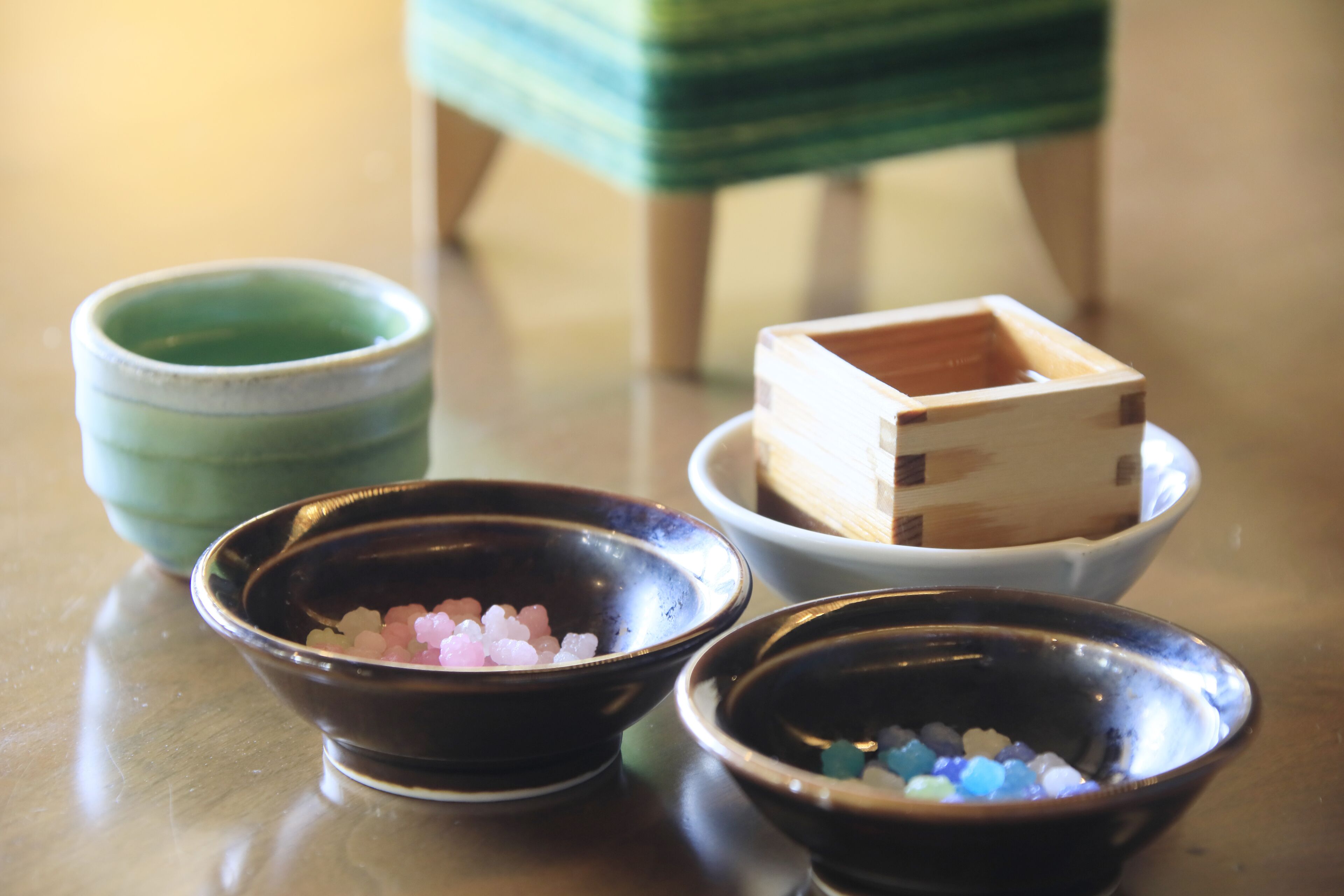 Four bowls with different colored salts on a reflective surface.