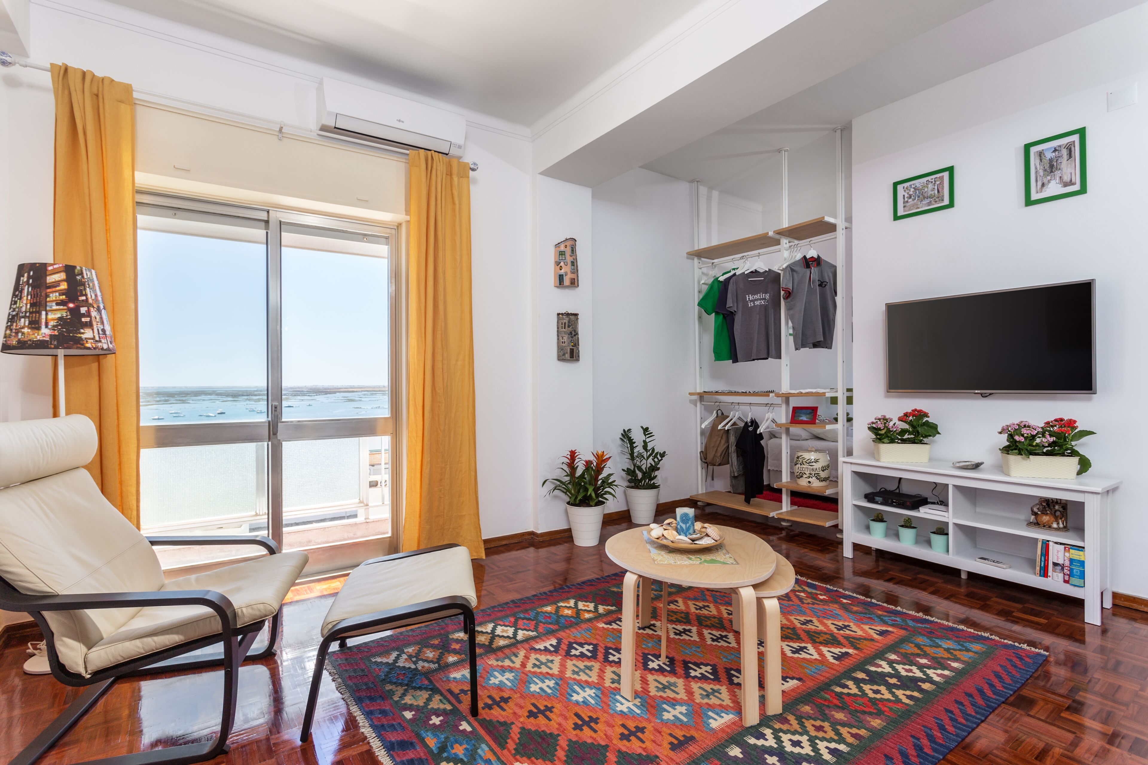 Una sala de estar moderna con un ventanal grande, un televisor, una zona de estar y un perchero.