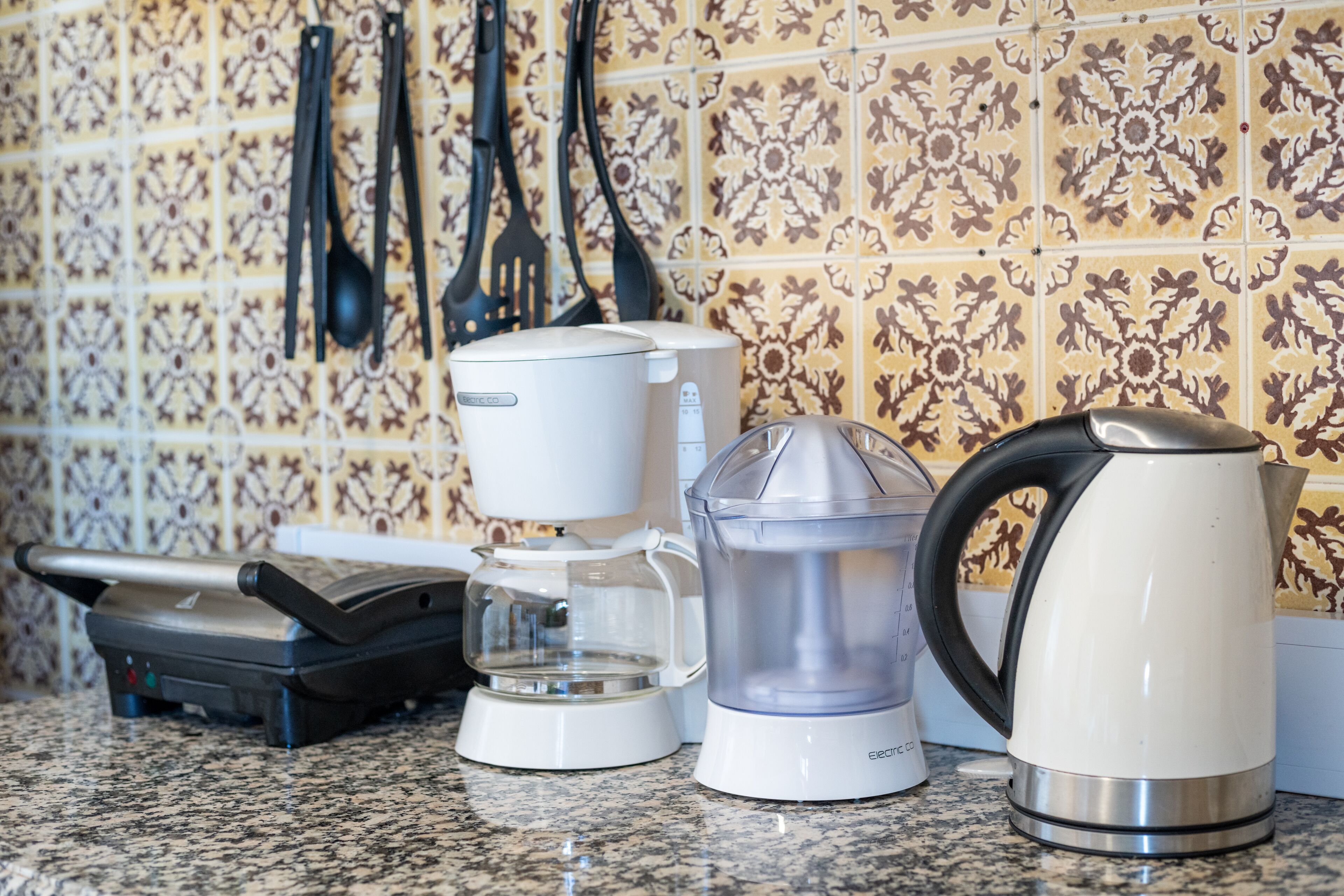 Una encimera de cocina con cafetera, hervidor y licuadora.