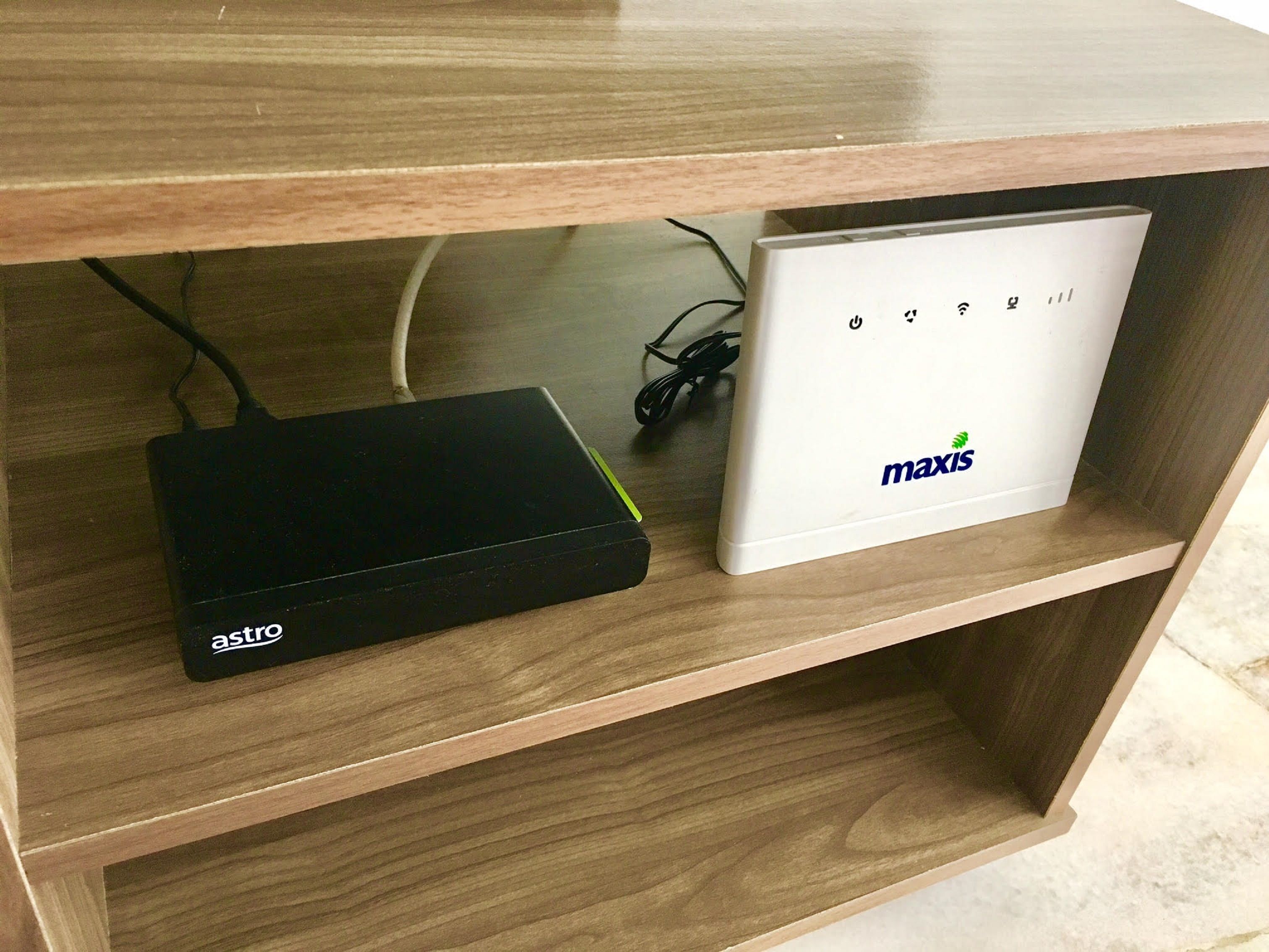 A wooden shelf with a black device labeled 'astro' and a white device labeled 'maxis'.