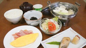 A table with various dishes including an omelet, sashimi, and a hot pot. - Yakehashiri Cabin Village (Hachimantai)