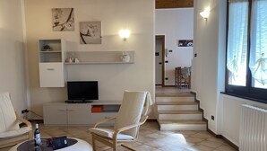 Un salon avec un téléviseur, des sièges et des œuvres d’art accrochées aux murs.