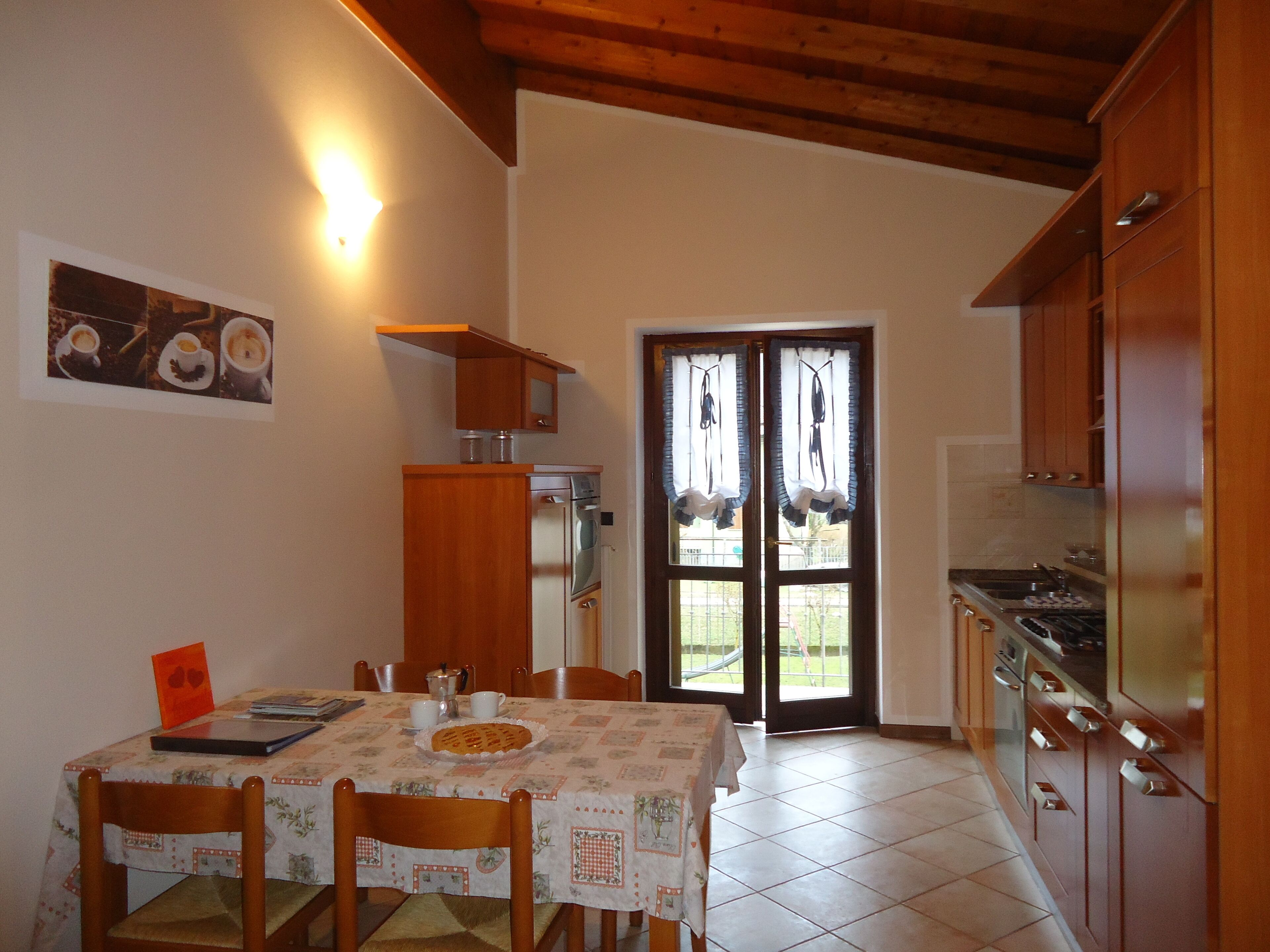 A dining area with a table set for two, a wooden cabinet, and a kitchen with a stove and oven.