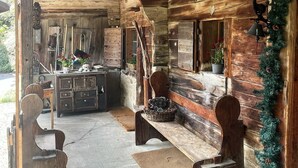 Interior rústico de una cabaña con paredes de madera, un banco, una mesa y un farol colgante.